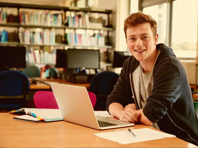 A boy from Denmark sitting with his laptop is taking virtual courses with EdOptions Academy.