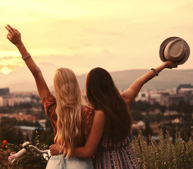 Two girls raising their arms to the sky, looking at the stunning view.
