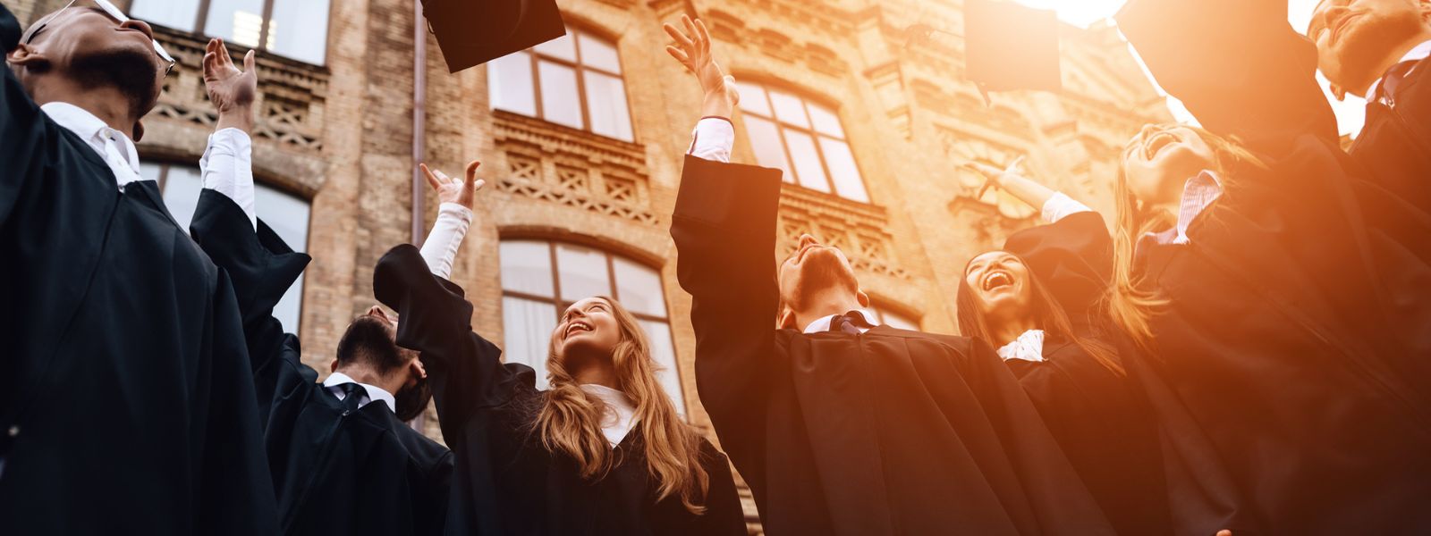 A group of students celebrating graduation day, throwing their caps in the air.