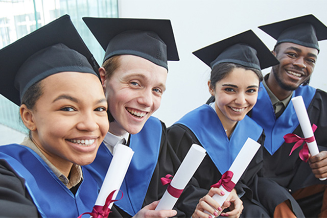 Four Academy online graduates wearing black cap and holding the diplomas.