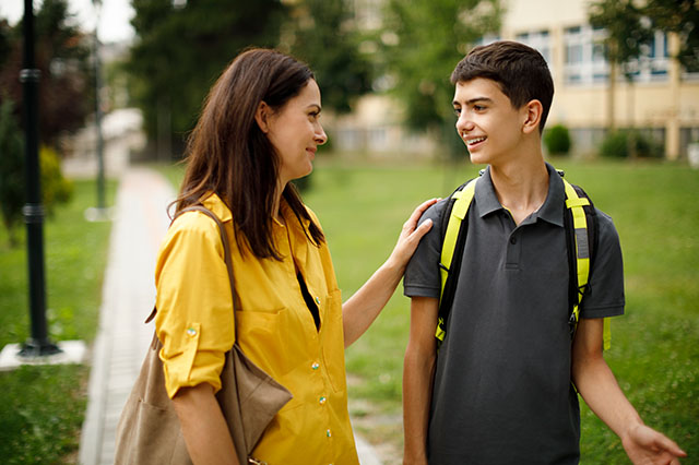 Academy online - Mother and teenage boy in front of school.