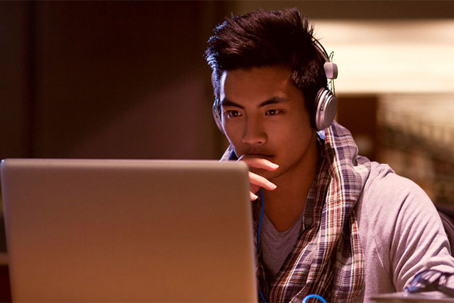 An asian boy student is studying online sitting in front of his laptop.