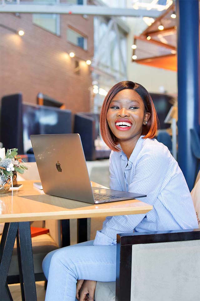 A female student sitting at a table with her laptop.