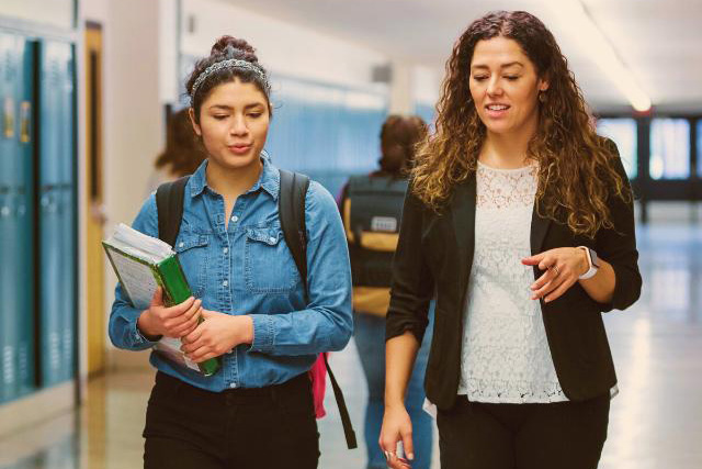 Student talking to teacher and walking from class.