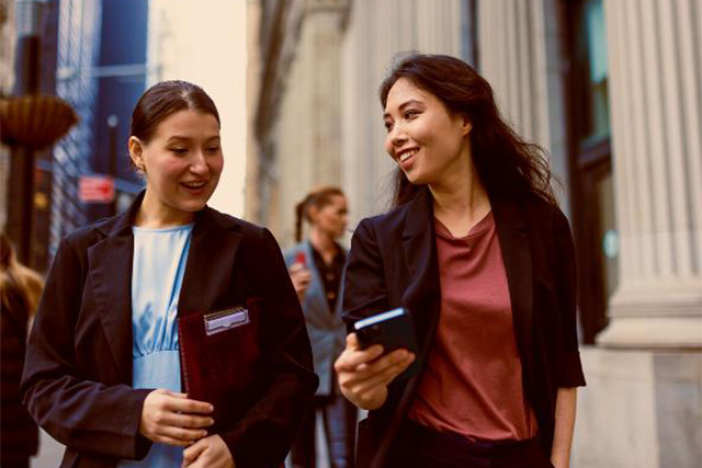 Two business women walking in city center.